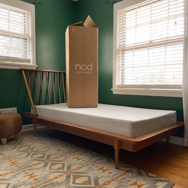 A furniture framework with a mattress and an upright container labeled