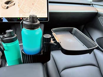 A reviewer's car with the extender in the cupholder, a large water bottle in that, and a tray off to the side