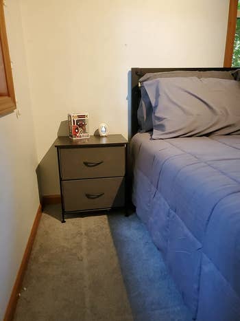 reviewer photo of gray fabric drawer nighstand next to bed