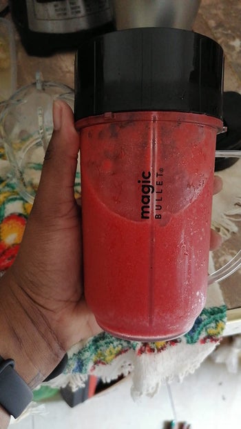 Reviewer holding a magic bullet with a red drink blended inside