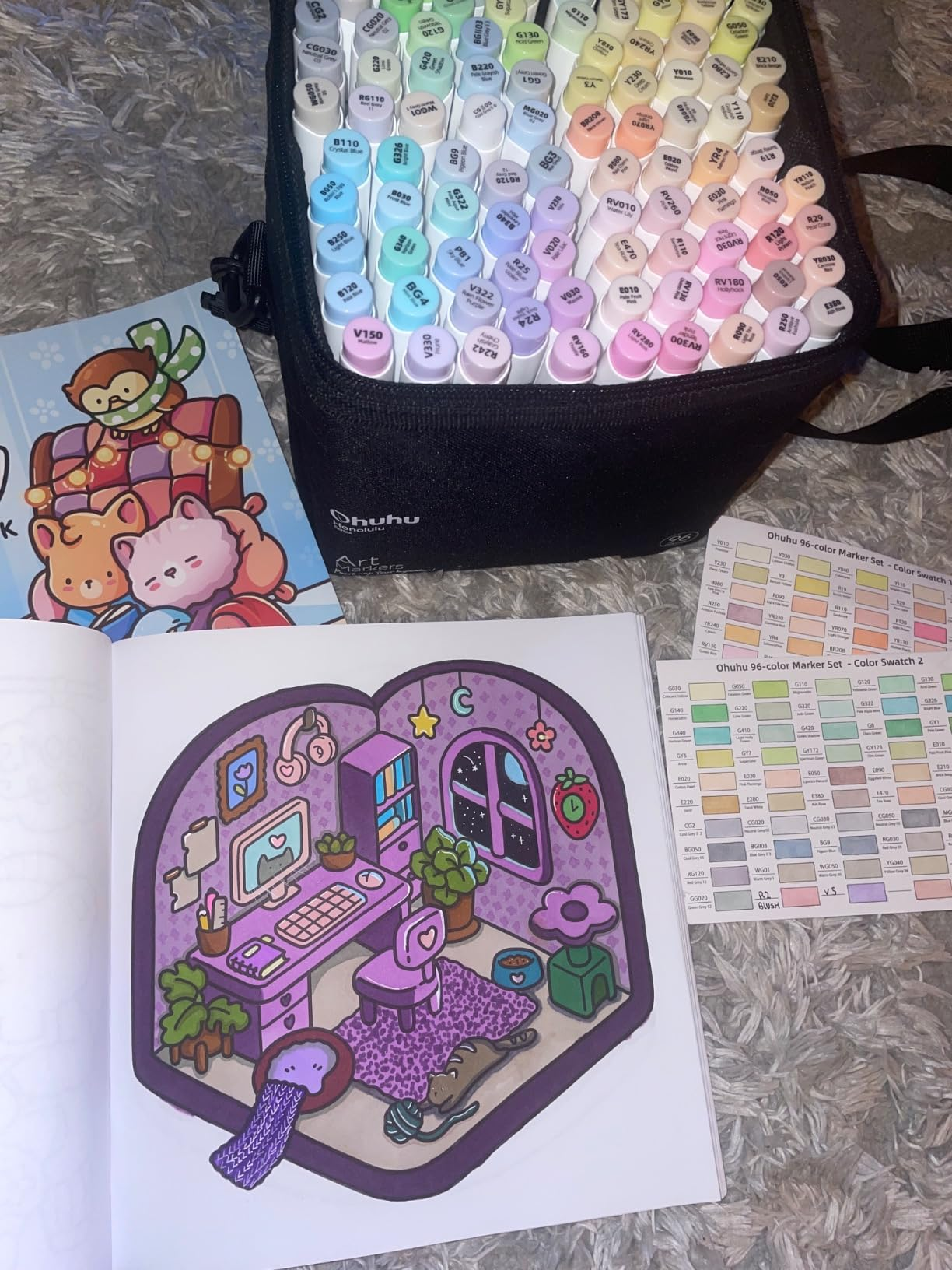 Markers in a case, a guide, and open book with a playful, cartoonish room design featuring a cozy reading nook with plants and décor on a fluffy surface