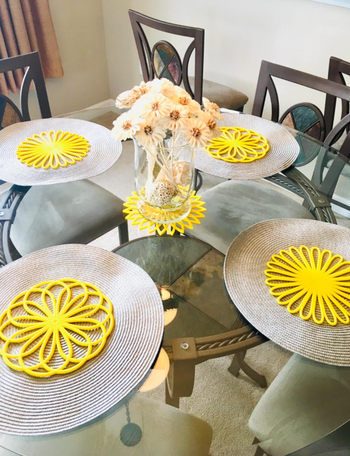 four large yellow floral shaped trivets on a dining room table 
