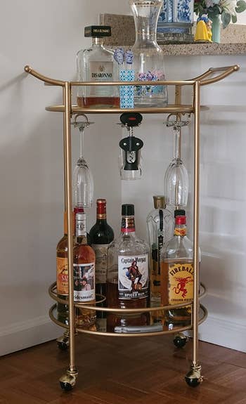 Reviewer image of the gold bar cart with bottles and glasses 