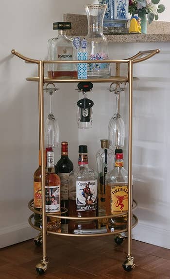 Reviewer image of the gold bar cart with bottles and glasses 