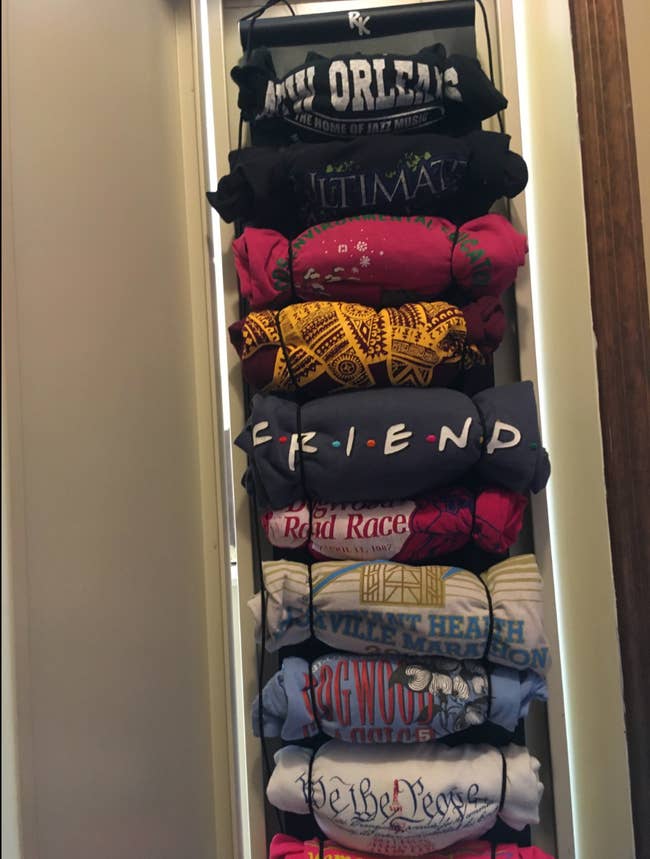 T-shirts rolled into ropes on a hanging organizer over a door 