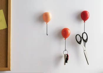 three small balloon shaped hooks in shades of red that are holding keys and scissors 