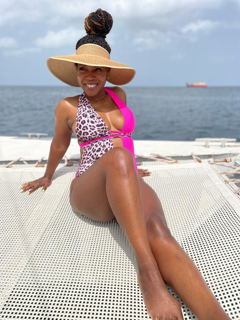 Reviewer successful  a stylish pinkish  and leopard people     swimsuit wearing the wide-brimmed visor 