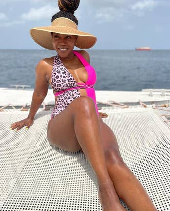 Woman in a stylish pink and leopard print swimsuit wearing the wide-brimmed visor 