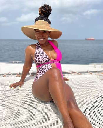 Woman in a stylish pink and leopard print swimsuit wearing the wide-brimmed visor 