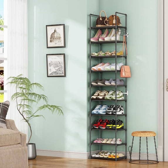 Tall achromatic metallic footwear rack successful country of a surviving room, holding assorted footwear and a handbag, adjacent to a tiny works and framed partition art