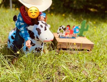 reviewer's child on cow bouncy pal wearing a cowboy hat