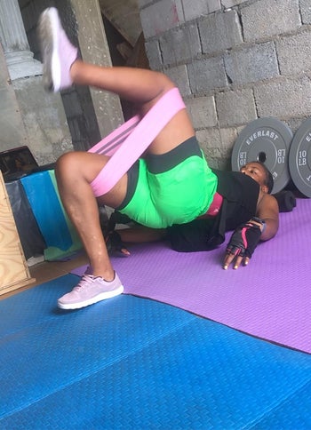 reviewer wears same pink band while completing leg raises on mat