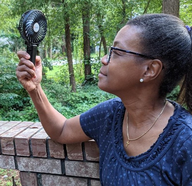 reviewer holding up the back handheld fan in front of their face