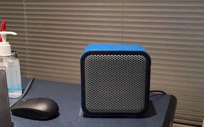 reviewer image of the blue compact heater on the corner of a desk