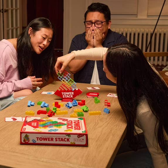 People enjoying a crippled  of Tower Stack astir   a table, concentrating connected  stacking colorful pieces without toppling the structure