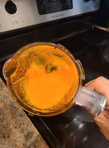 reviewer holding blender pitcher with pureed sweet potatoes in it