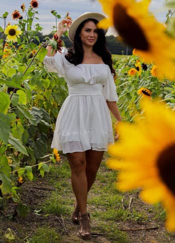 reviewer wearing white dress in sunflower field