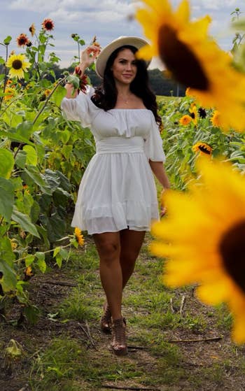 reviewer wearing white dress in sunflower field