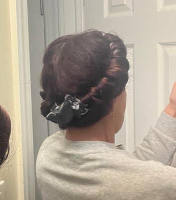 reviewer with hair wrapped around a heatless curling rod secured with scrunchies