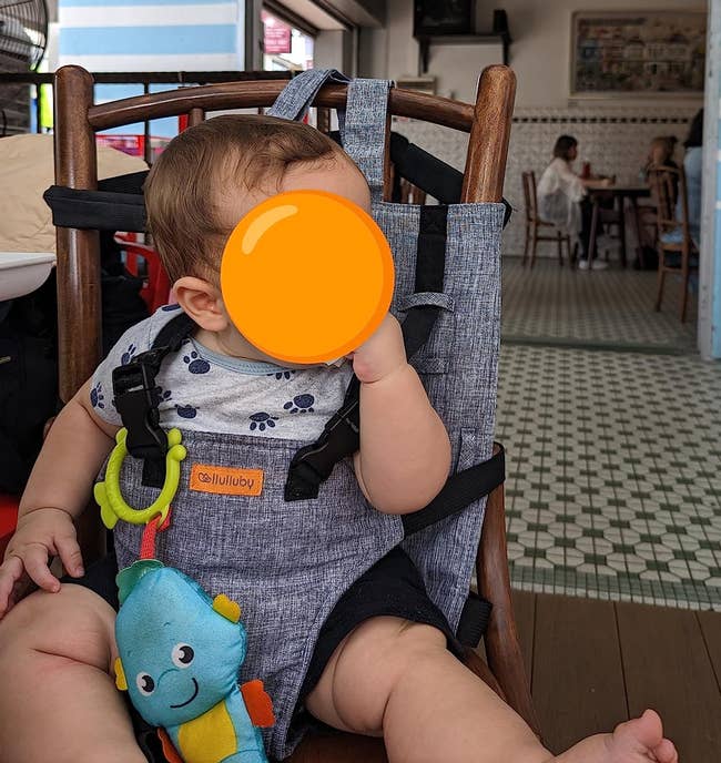 reviewer's child at a restaurant sitting in a char while secure in the harness