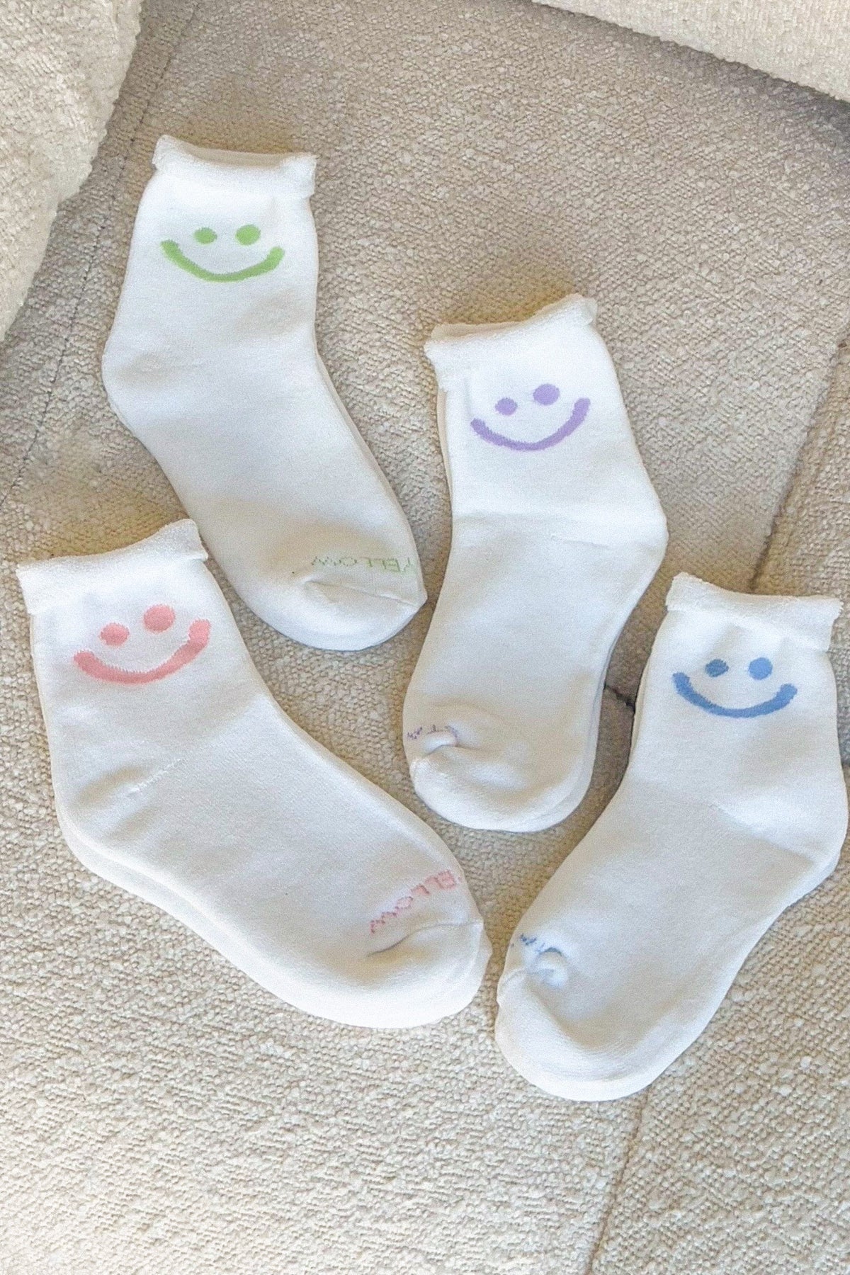 four white socks with pastel smiley faces on them