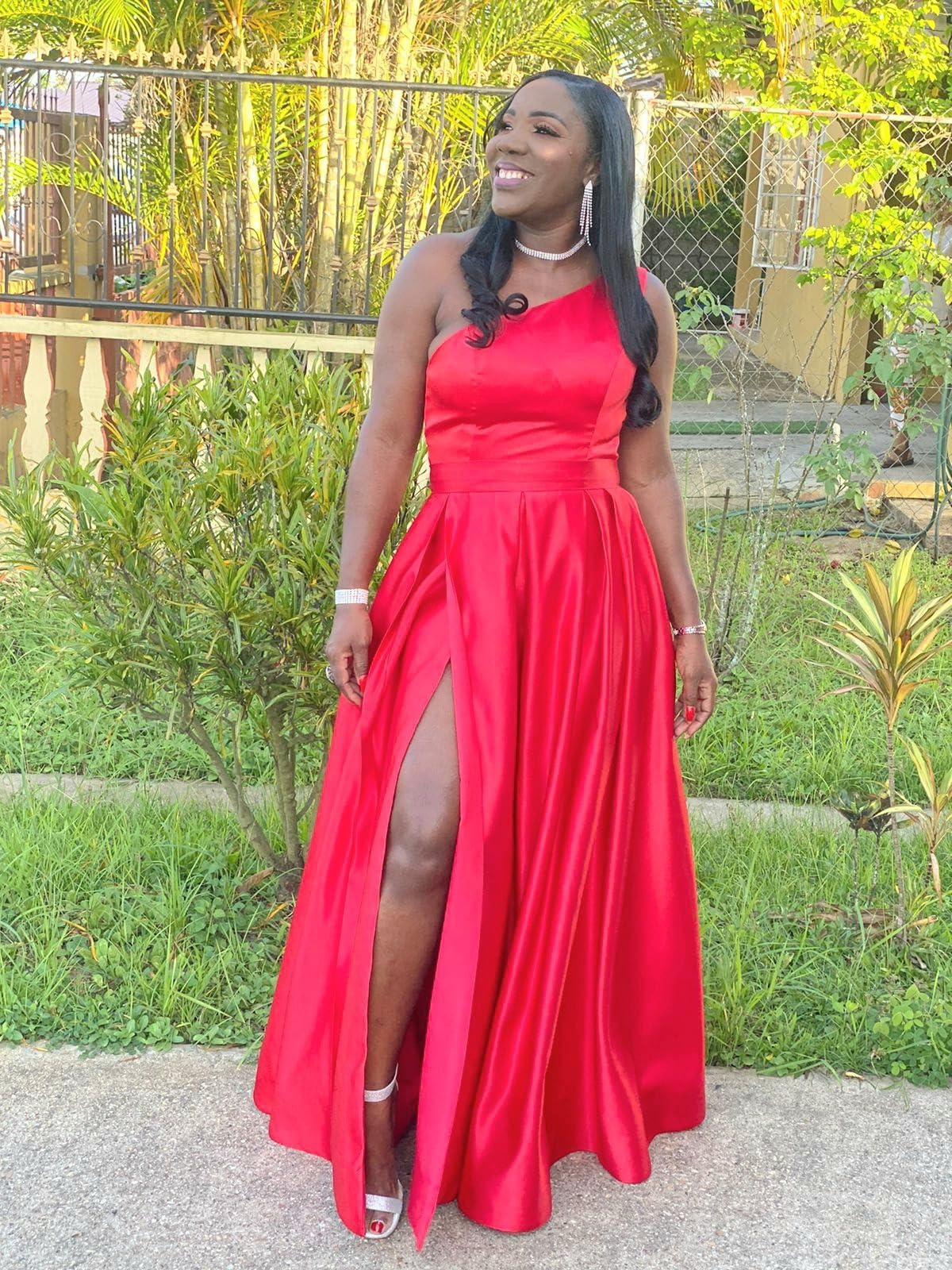 Reviewer in elegant red gown with a high slit, smiling in an outdoor setting. Not a known personality