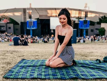 reviewer photo sitting at outdoor festival on green plaid picnic blanket