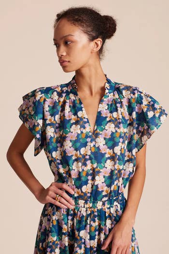 model wearing the blue, white, and green floral blouse