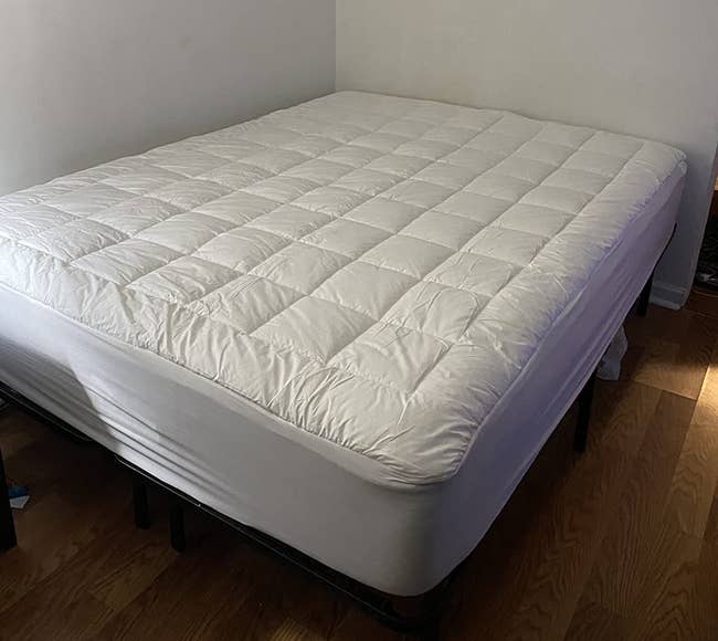 a reviewer photo of the mattress topper on a mattress 