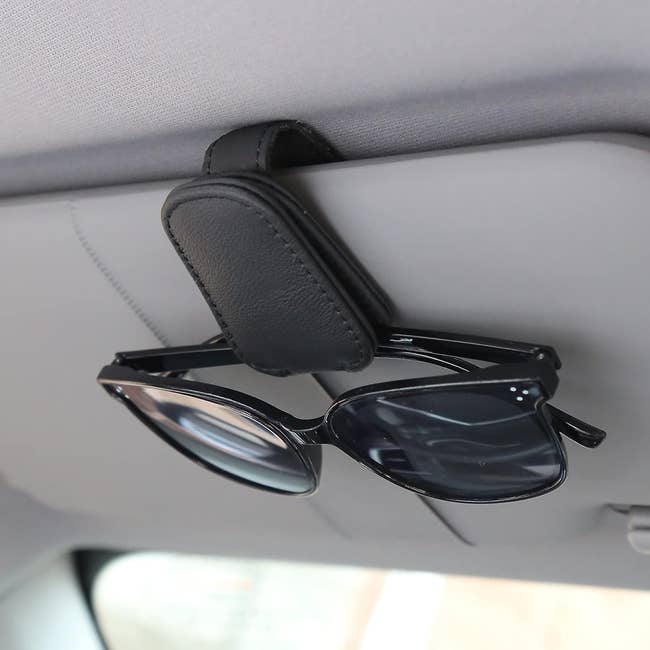 small black magnetic clip on a car visor holding sunglasses in place 