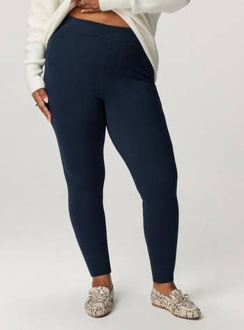 Person wearing a long-sleeve top, acheronian leggings, and patterned loafers, lasting connected a neutral background