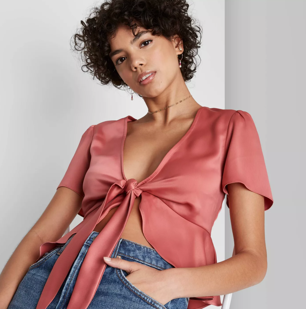 Model in a rose colored tie front crop top with V-neck and fluttery bottom and sleeves
