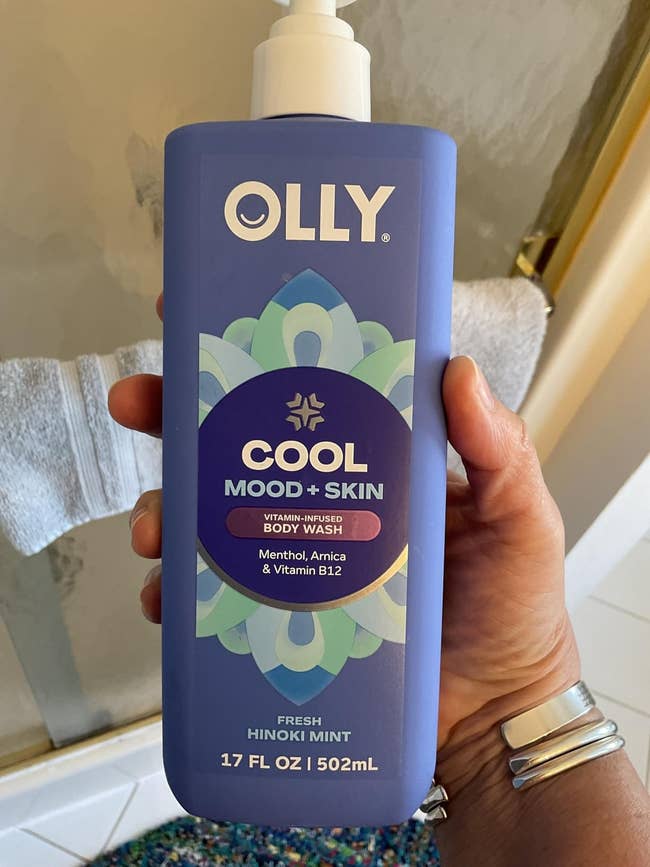 Person holding a vessel  of OLLY Cool Mood + Skin Body Wash, featuring menthol, arnica, and vitamin B12 successful  a 17 fl oz size