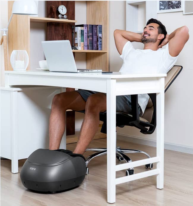 model using the foot massager while sitting at a desk