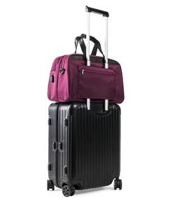 the plum colored bag attached to a luggage handle via its back strap