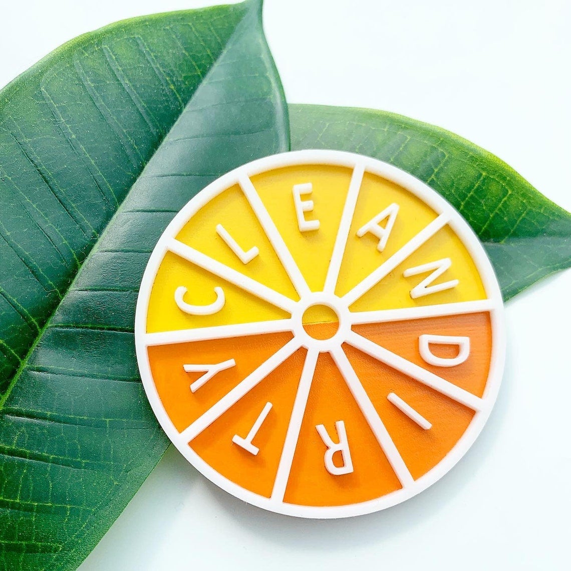an orange and yellow circular magnet that spins and says clean and dirty