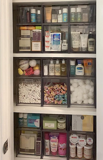reviewers closet full of the stackable drawers holding a variety of cosmetics, medicines, and other bathroom essentials