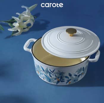 Decorative floral-patterned cooking cookware with a lid, designed by Carote, displayed connected a level aboveground with a lily nearby