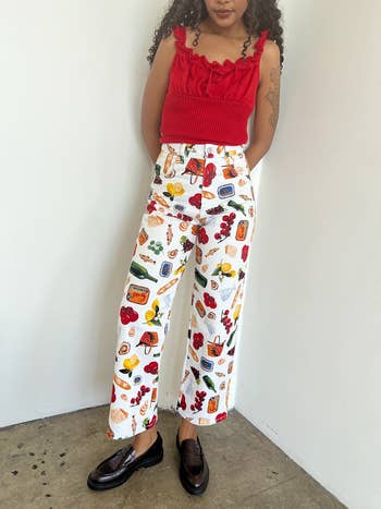 Person in a ruffled top and printed pants paired with loafers, standing with hands slightly behind