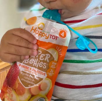 reviewer's child holding food pouch with mouth on food pouch top
