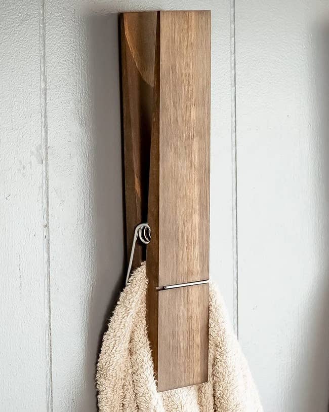 giant wooden clothespin mounted on wall and holding a towel