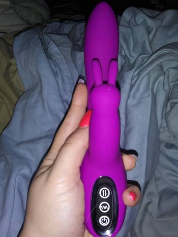 Hand holding pink triple vibrator and displaying buttons