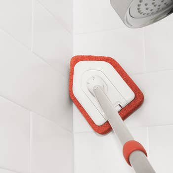the scrubber being used to clean tiled walls in a shower