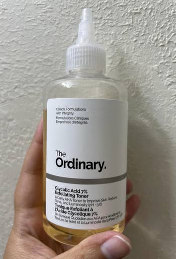 A hand holds The Ordinary Glycolic Acid 7% Exfoliating Toner bottle