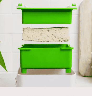 gif of the green and white tofu press squeezing a block of tofu