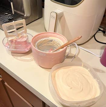 reviewer's small ice cream machine next to a container of fresh ice cream