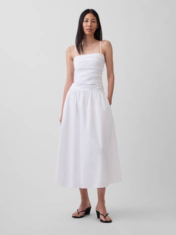 Person wearing a ruched midi formal with spaghetti straps, paired with minimalist sandals