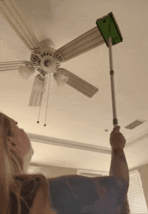 Person utilizing an extendable duster to cleanable  a ceiling instrumentality   successful  a home, demonstrating an casual  cleaning instrumentality   for hard-to-reach places