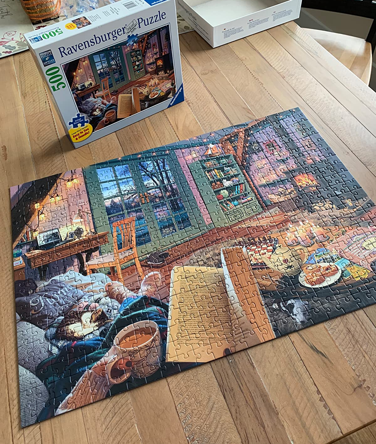reviewer photo of the completed cozy retreat puzzle in front of the puzzle box