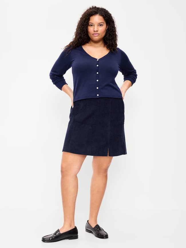 Model wearing a button-up cardigan and a knee-length skirt with loafers